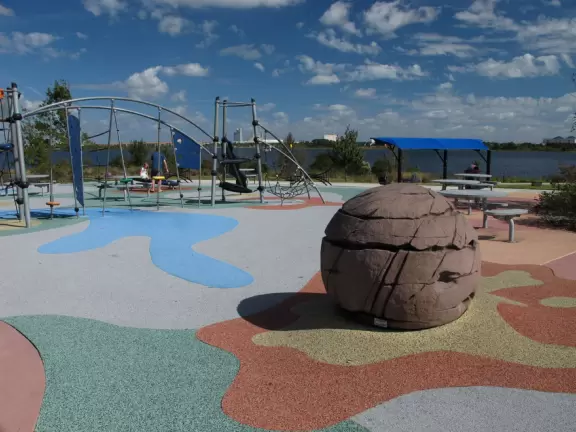 Huge space-age playground for big kids plus toddler playground and splash pad with view of the blue lake.