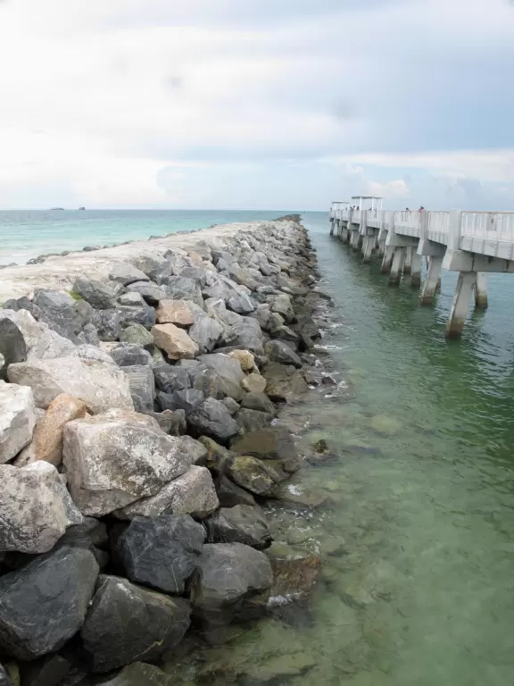 Modern pier, grass hill with winding paths, space-age playground and splash pad, and shady promenade along the water.