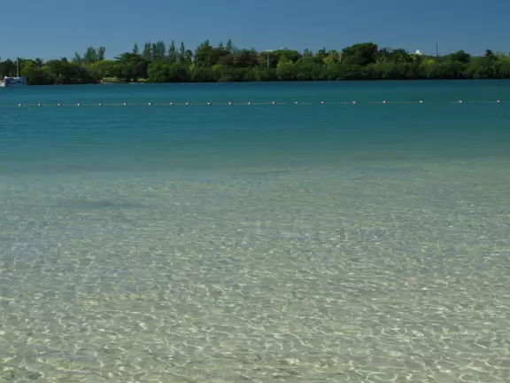 Sheltered cove with blue-green water, bright green playground, and river for paddling.