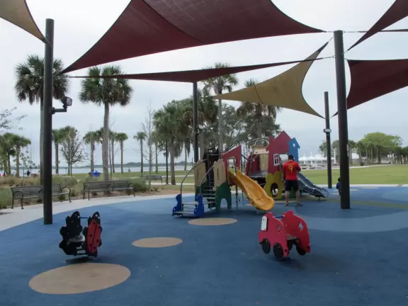 Beautiful lakefront park with wide walking paths, lighthouse, water lilies and other water flowers, birds, large playgrounds, and marina.