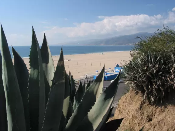 A winding walkway above the clay-red cliffs of Santa Monica, with stunning beach and mountain views.