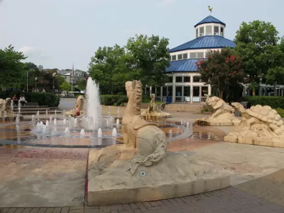 Carousel and splash pad in a park on the river with views of the blue bridge.