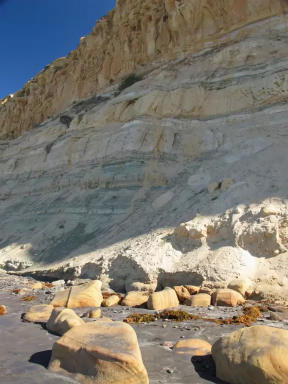 Beach with sparkling black sand, and hike atop high red cliffs with views.