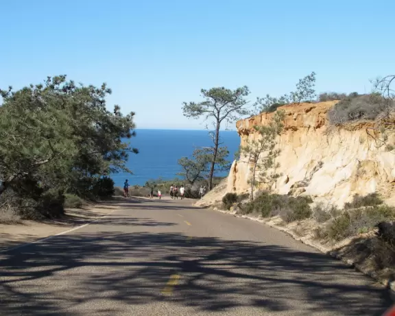 Beach with sparkling black sand, and hike atop high red cliffs with views.