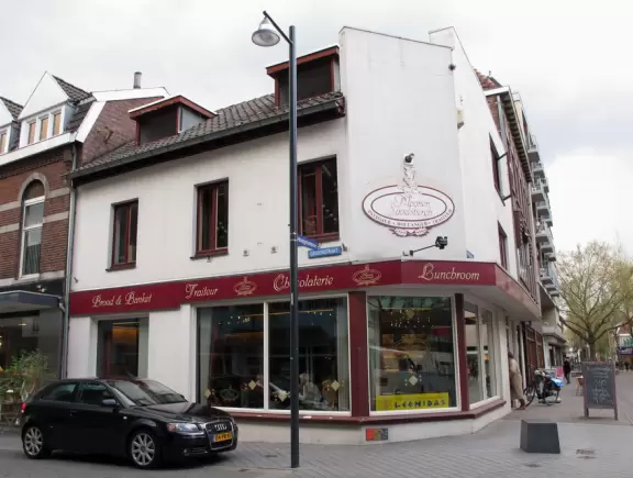 Town center with historic storefronts, large square, stone church, and outdoor cafes with flowerboxes.