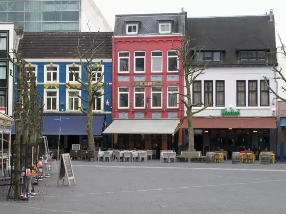 Town center with historic storefronts, large square, stone church, and outdoor cafes with flowerboxes.