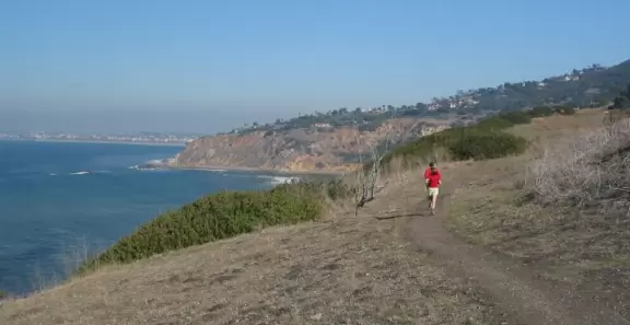 A winding path along steep cliffs with views of stunning rocky coves below.
