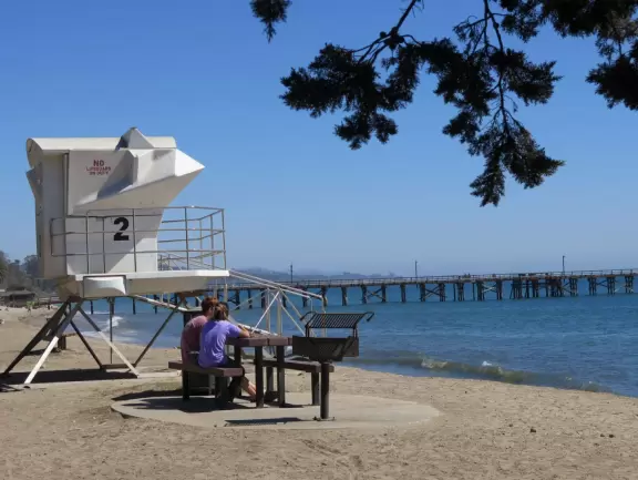 Festive beach with white cliffs, popular playground, pier, and cafe coming soon.