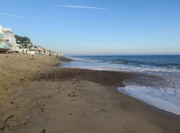 Beautiful beach with big pebbles at the shore, and mansions almost right up to the water.