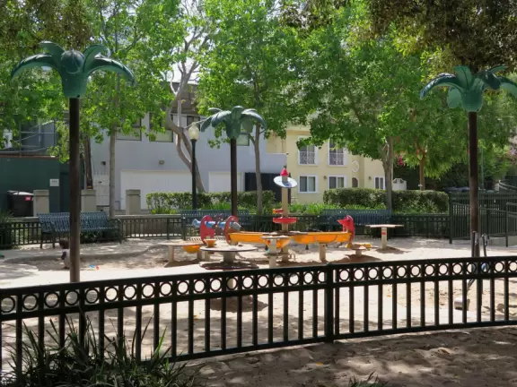 Large playground for big and little kids, with shade canopy, redwood trees, and walkway around the park.