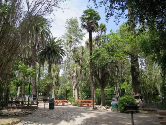 Park with playground surrounded by tropical plants and trees, lawn bowling, and putting green in the center.