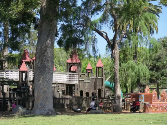 Giant wooden castle playground set among tropical palms.