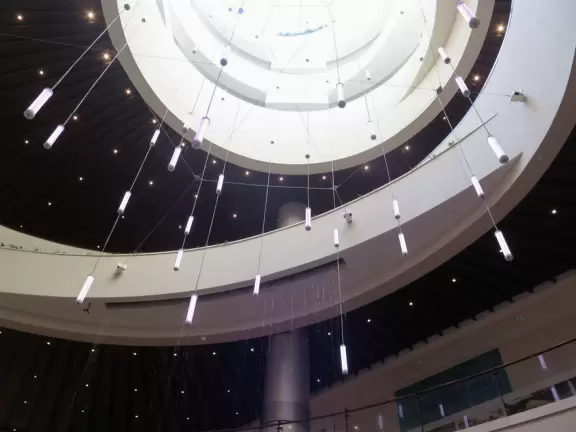 An outdoor mall under a huge banyan tree hung with lanterns. Beautiful flowers by a stream, rock-like seats kids love, and rain fountain.