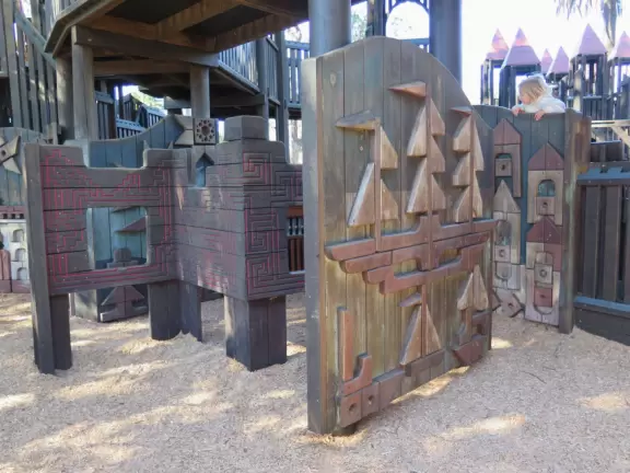 Giant wooden castle playground set among tropical palms.