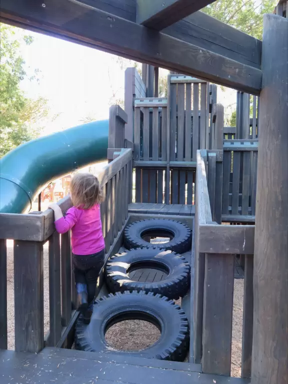 Giant wooden castle playground set among tropical palms.