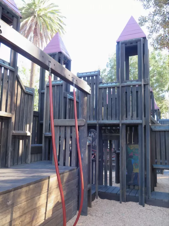 Giant wooden castle playground set among tropical palms.