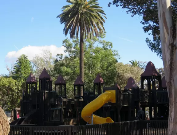 Giant wooden castle playground set among tropical palms.