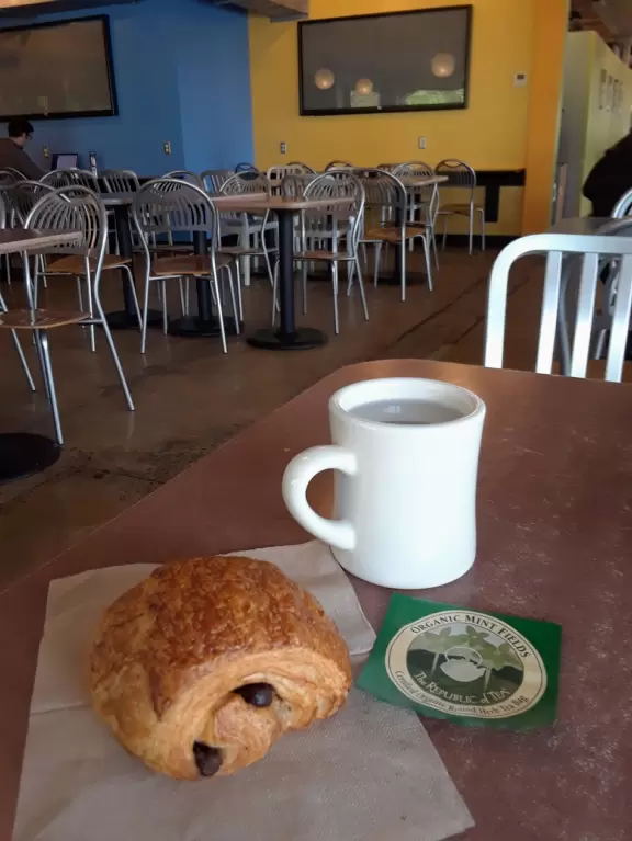 Health food store with great bakery, indoor seating with&nbsp;big windows, and outdoor picnic tables under thick leafy shade.
