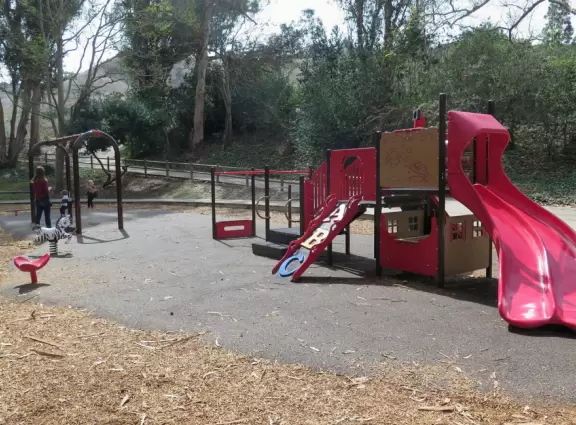Toddler playground in a sunken area filled with eucalyptus trees.