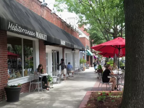 Cute downtown area with big trees, sidewalk cafes, and brick buildings.