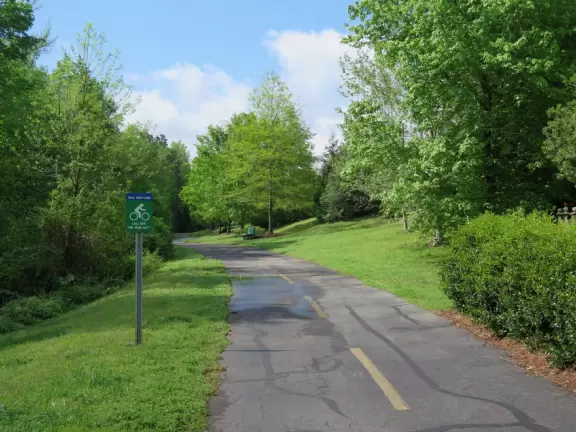 Gorgeous one-mile greenway or bike path with shady forest, flowers, little hills, and pond with fountain.