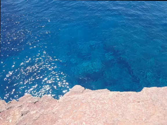 Barren, exposed, windy area where people jump off cliff and then climb a rusty, windwhipped ladder back up.