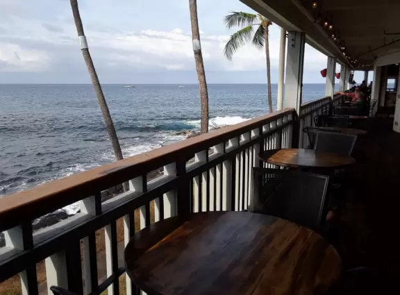 Lovely main street Alii Drive along the crystal clear ocean, backed by high mountains, with historic buildings, oceanfront cafes, and touristy shops.