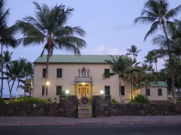 Lovely main street Alii Drive along the crystal clear ocean, backed by high mountains, with historic buildings, oceanfront cafes, and touristy shops.