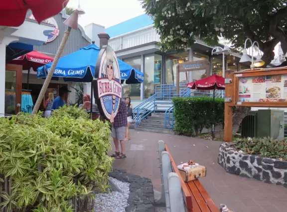 Lovely main street Alii Drive along the crystal clear ocean, backed by high mountains, with historic buildings, oceanfront cafes, and touristy shops.