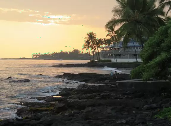 Lovely main street Alii Drive along the crystal clear ocean, backed by high mountains, with historic buildings, oceanfront cafes, and touristy shops.