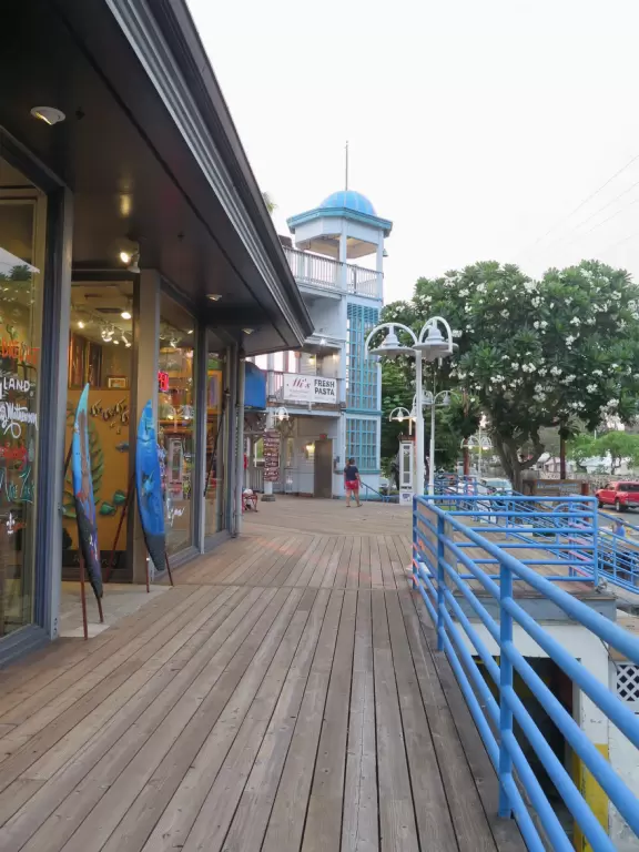 Lovely main street Alii Drive along the crystal clear ocean, backed by high mountains, with historic buildings, oceanfront cafes, and touristy shops.