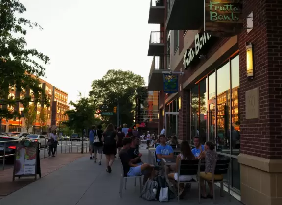 Cute downtown area with big trees, sidewalk cafes, and brick buildings.