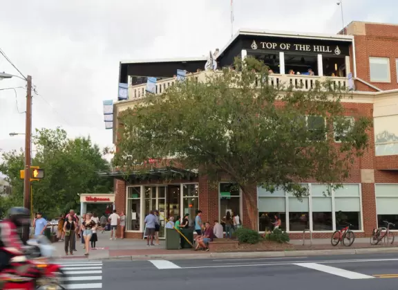 Cute downtown area with big trees, sidewalk cafes, and brick buildings.