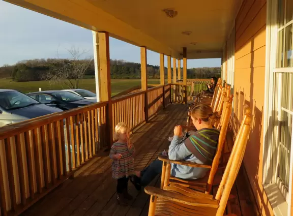 Wide patio with rocking chairs looking out on farmland.