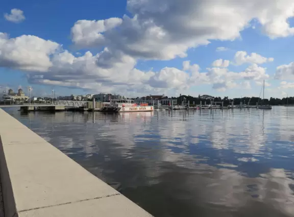 Wide walking path along the water with tropical flowers, piers, grand high rises, and palm trees- no shade though.