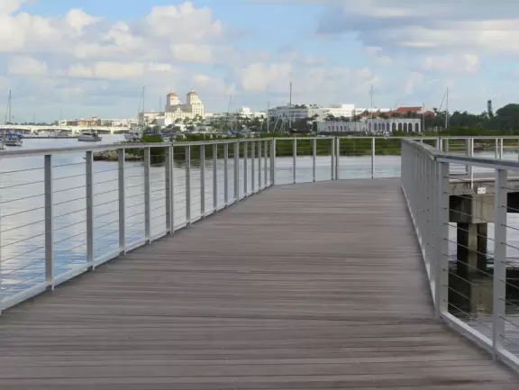 Wide walking path along the water with tropical flowers, piers, grand high rises, and palm trees- no shade though.