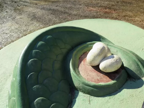 Wonderful playground with dragon on little hills, many different play areas, winding paths, and landscaping.