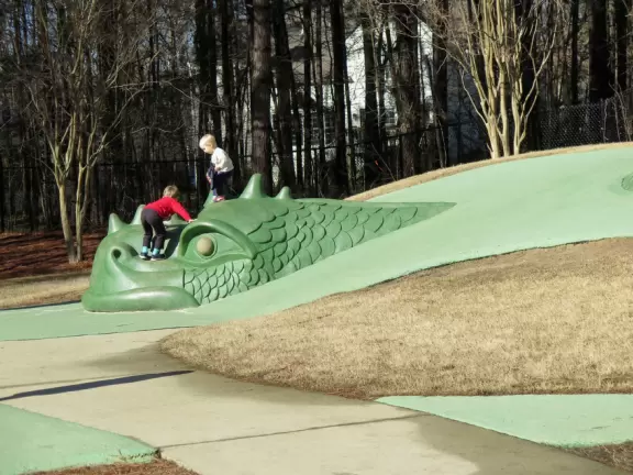 Wonderful playground with dragon on little hills, many different play areas, winding paths, and landscaping.