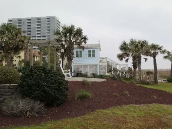 Cute little park with flowers, small playground, and swings, by the sea.