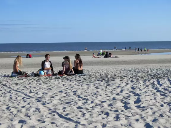 Wide white sand beach with lots of people enjoying the pleasant vibe. Bench swings and splash pad.
