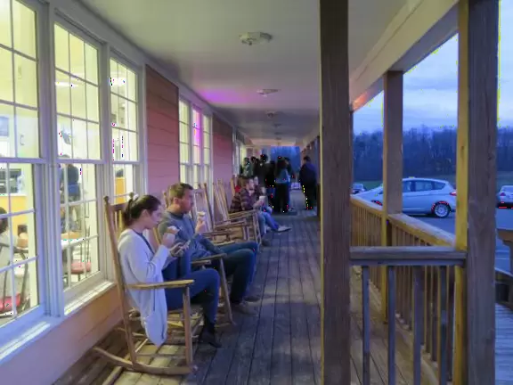 Wide patio with rocking chairs looking out on farmland.