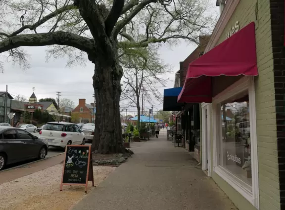 Cute downtown area with big trees, sidewalk cafes, and brick buildings.