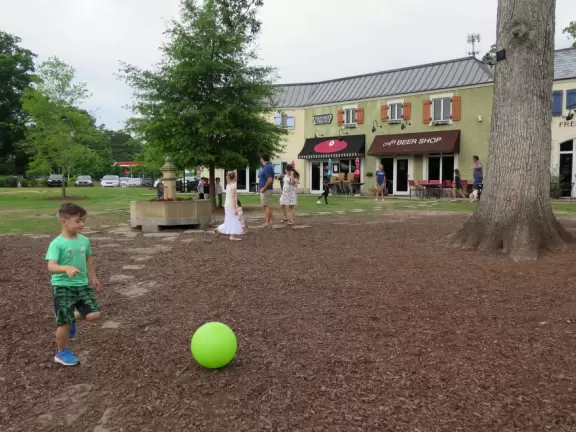 Stark French-style outdoor shopping center with large lawn for kids to play.