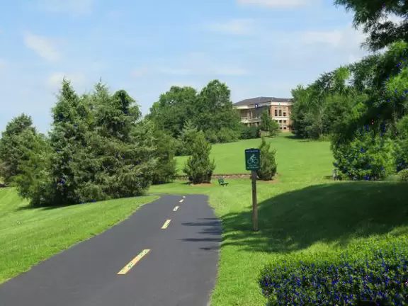 Gorgeous one-mile greenway or bike path with shady forest, flowers, little hills, and pond with fountain.