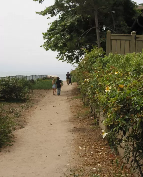 A walk under a canopy of tropical flowers to a beach fronted by luxury homes.