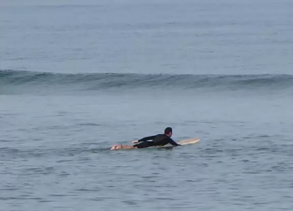 Blue-green water, rough surf, and a wooden boardwalk for shade.
