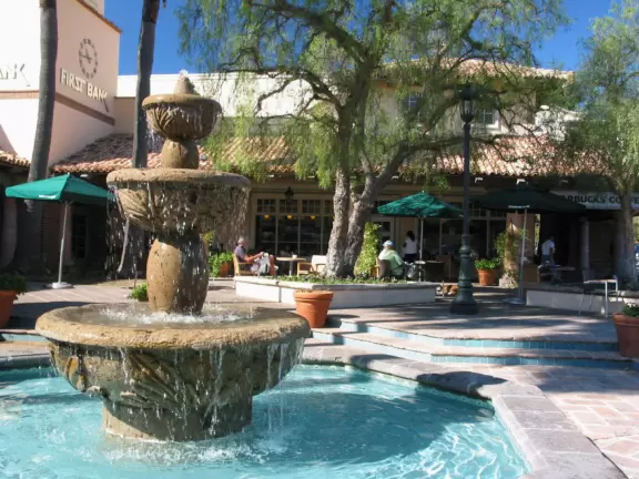 Spanish-style shopping center with chic people having coffee by the outdoor fountain.
