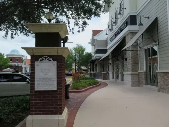 Large shopping center with big box stores and a small walkable area, in a cookie-cutter style town.