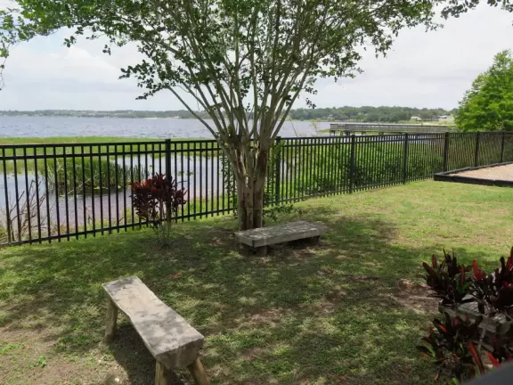 Small strip of land between bike path and lake, with fenced playground and pier.