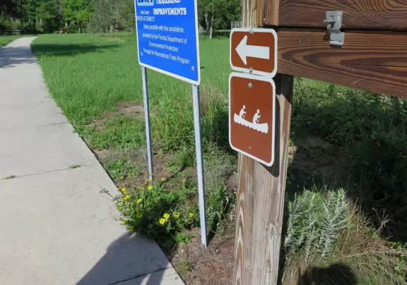 Shady white sand walking trails, and a dock on the Crooked River, with cute cypress trees and wildflowers along the path.